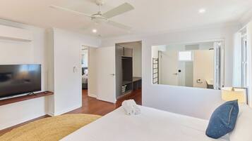 Une chambre d’hôtel avec un lit, une télévision, un ventilateur de plafond, une armoire et une salle de bain visible à travers une porte ouverte.