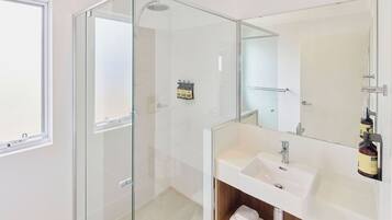 Un bagno moderno con doccia vetrata, lavandino bianco e uno specchio grande.
