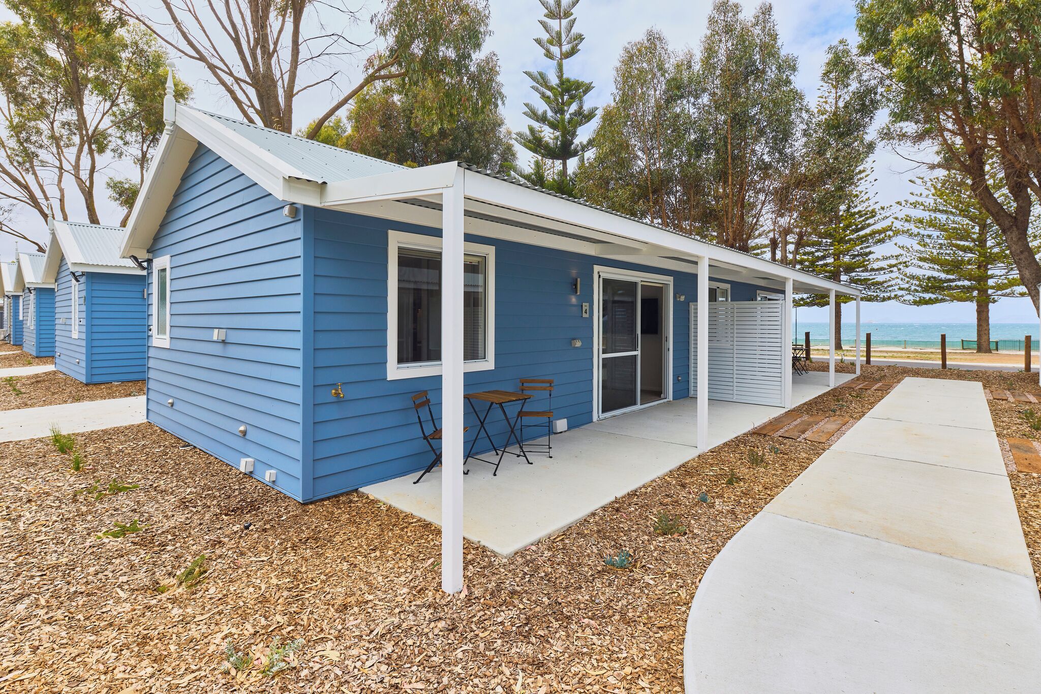 A blue single-story building with a covered patio and a view of the ocean.