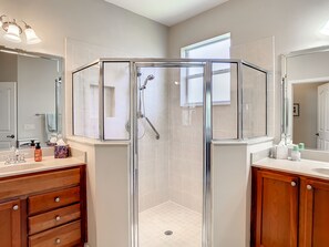 Un baño moderno con ducha de vidrio, tocador con espejo y armarios de madera.