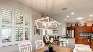Una cocina moderna con armarios de madera, una isla central y un comedor con sillas blancas.