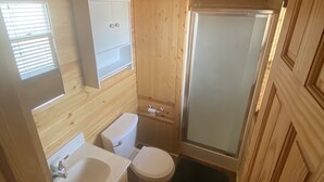 Un bagno in legno piccolo e funzionale, con lavandino, WC e doccia.
