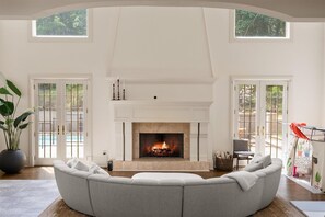 Cozy up by the fireplace in this inviting living room with a vaulted ceiling and large windows.