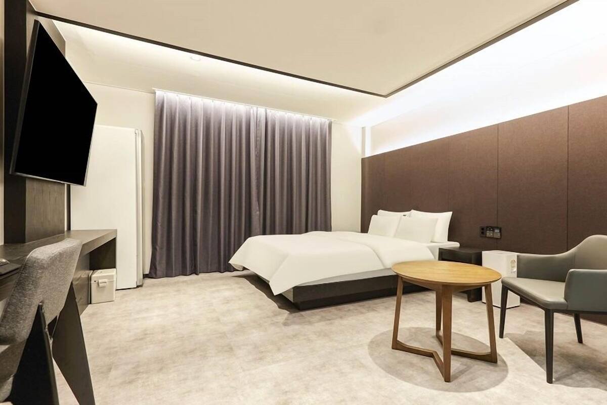 Een moderne hotelkamer met een bed, een bureau, een stoel en een televisie.