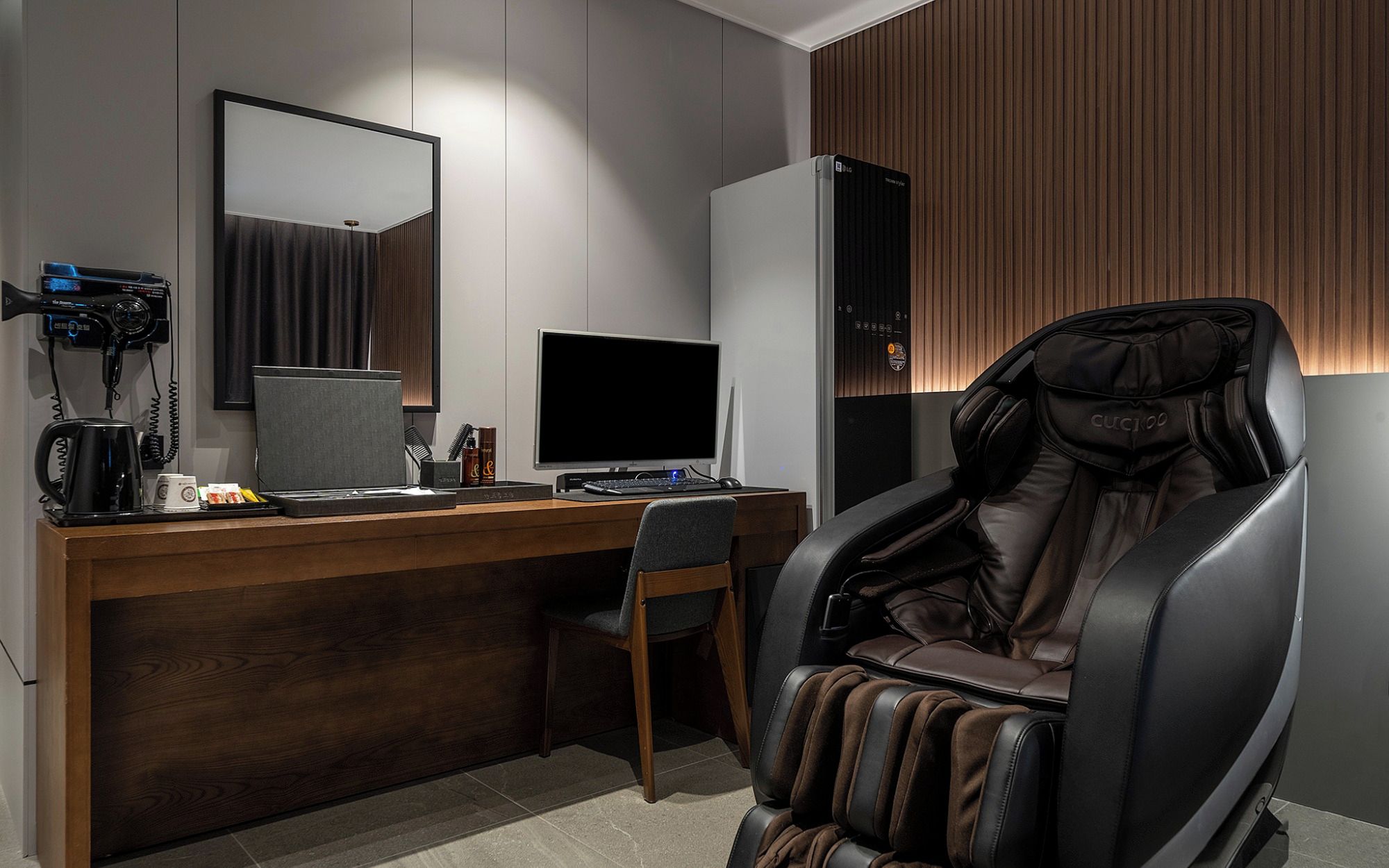 Un espacio de oficina moderno con un escritorio, computadora y sillón de masaje.