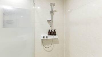 A shower with a handheld showerhead and a wall-mounted faucet, a control panel, and two bottles of body wash.