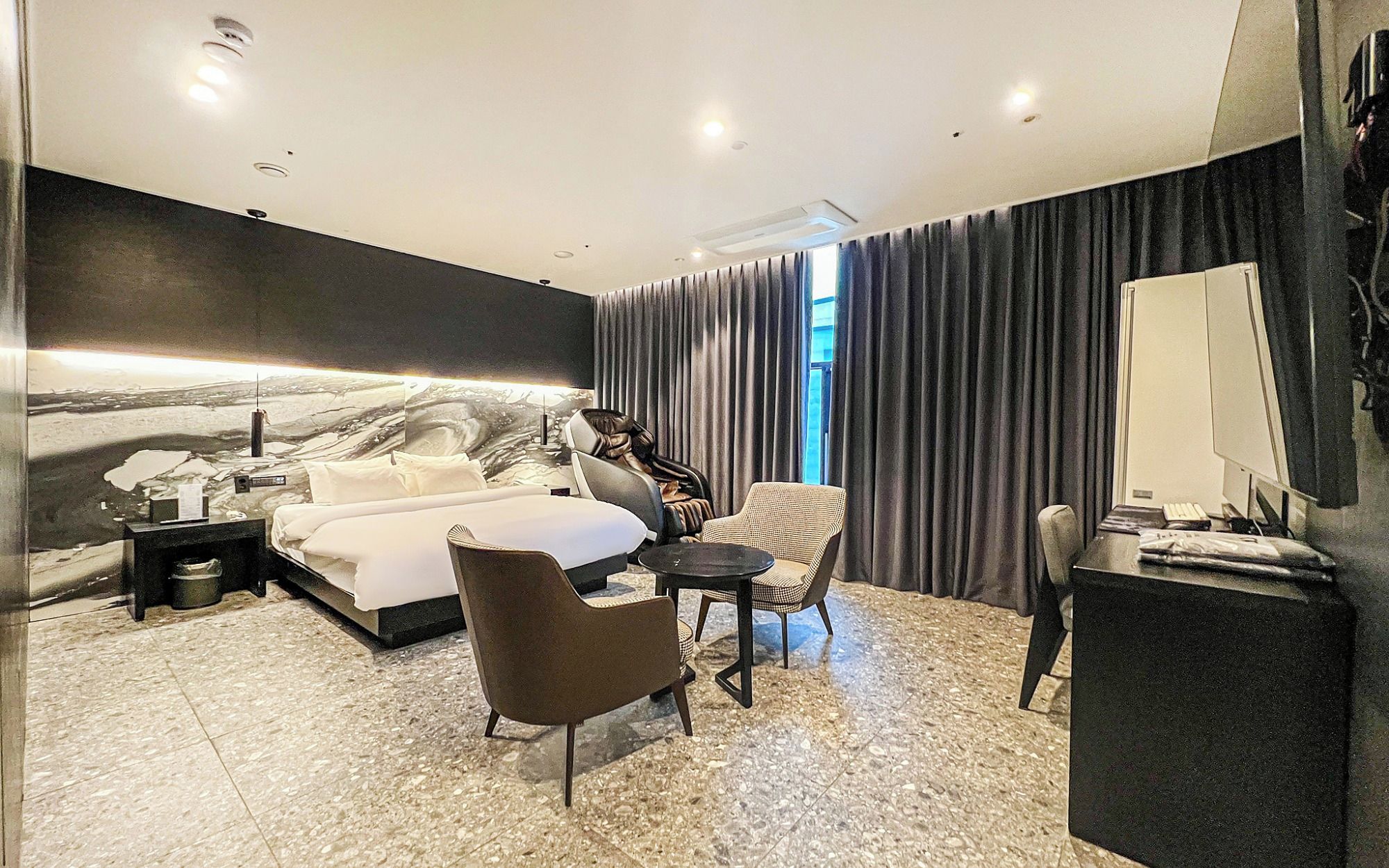 Une chambre d’hôtel moderne, dotée d’un grand lit, d’un bureau, d’une chaise et d’un canapé.