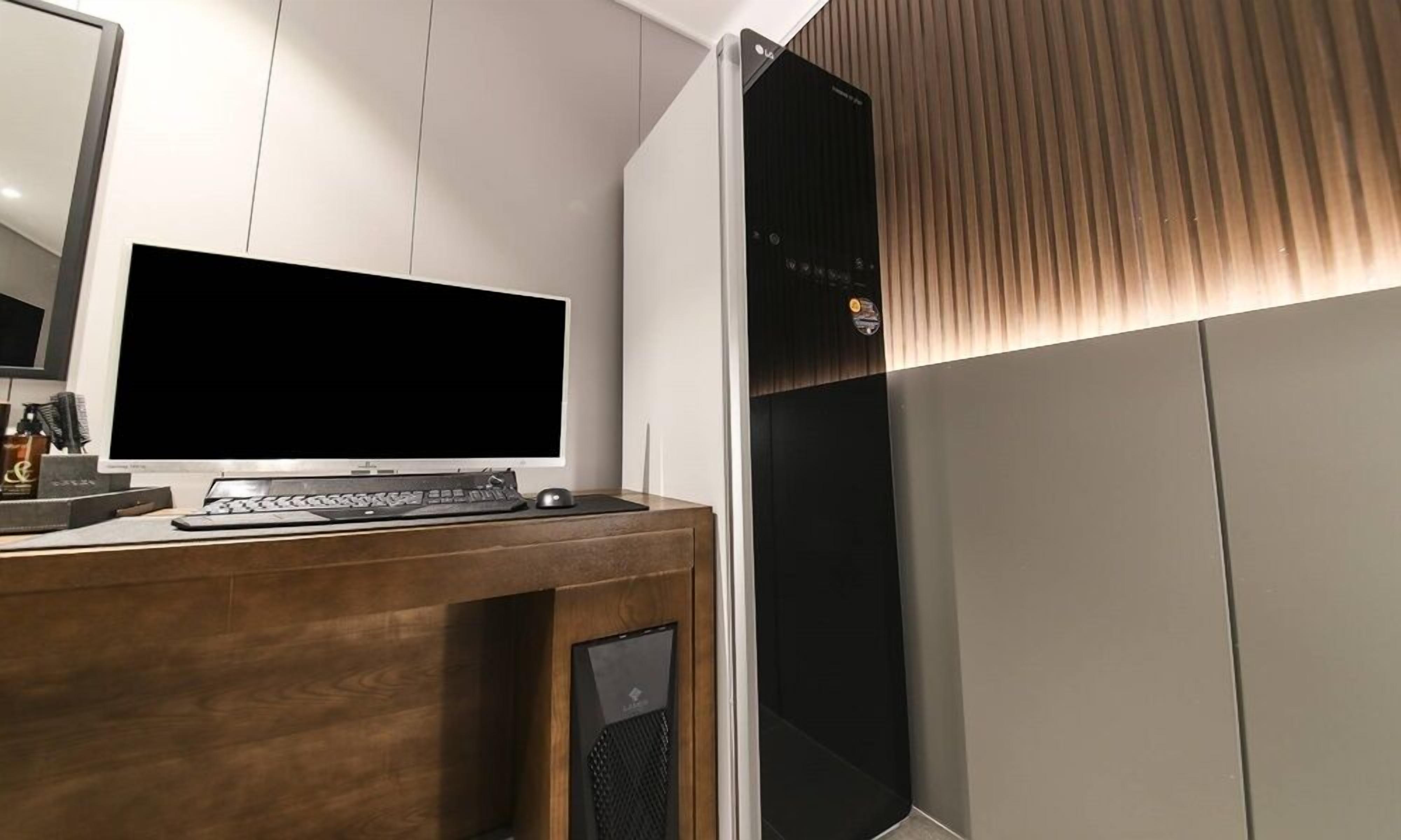 A modern room with a wooden desk, a flat-screen TV, and a black speaker.