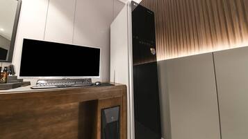 A modern room with a wooden desk, a flat-screen TV, and a black speaker.