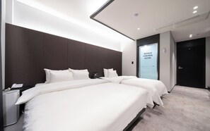 A hotel room with a large bed, a bedside phone, and a wall-mounted air conditioning unit.