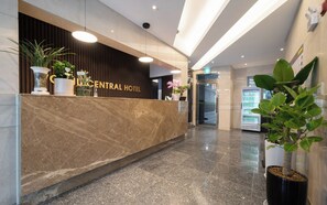 A hotel reception desk with a marble counter, potted plants, and a vending machine. - Wonju Central Hotel (Wonju)