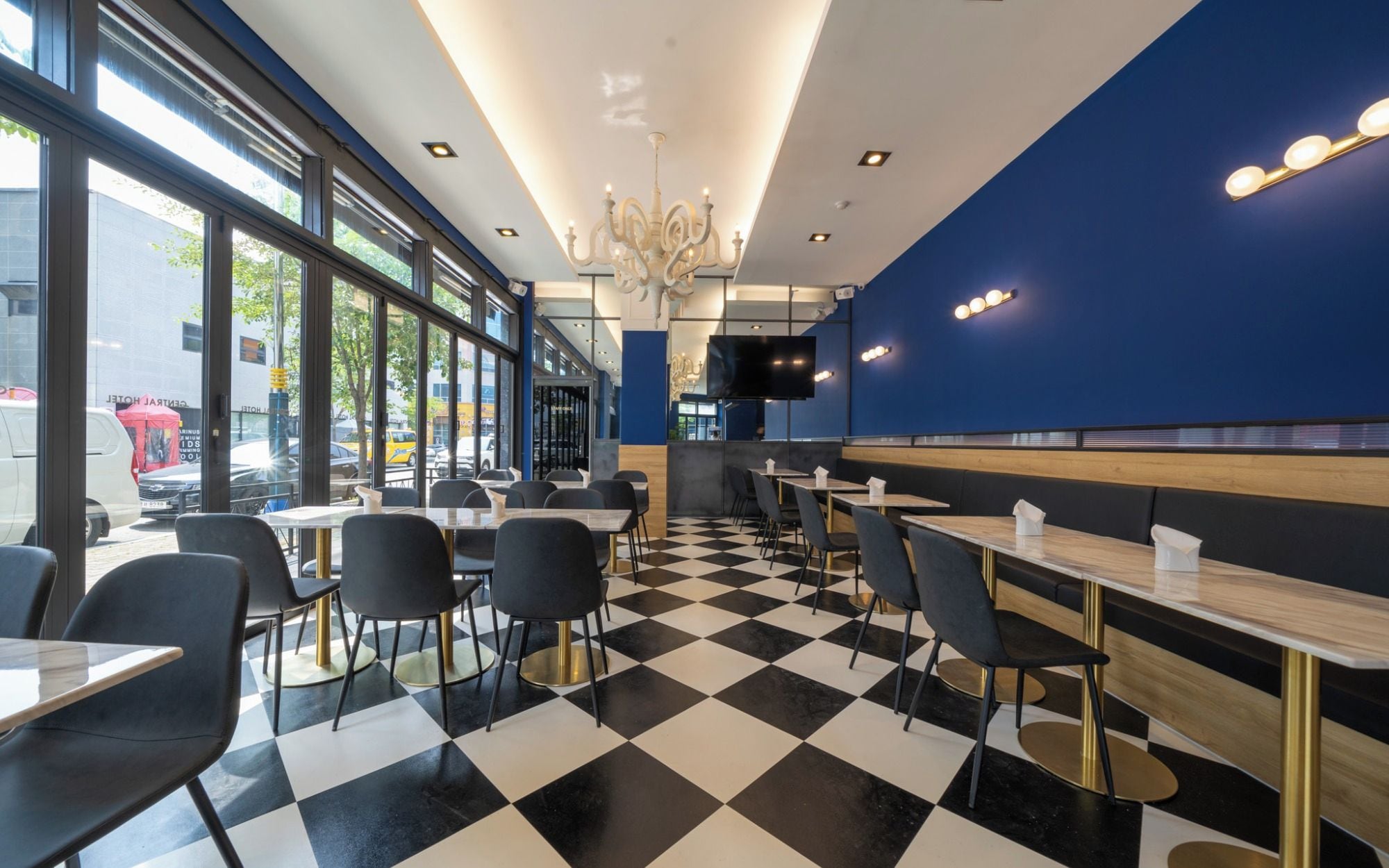 Un interior de restaurante moderno con suelo a cuadros, sillas negras y blancas, y una pared azul de acento.