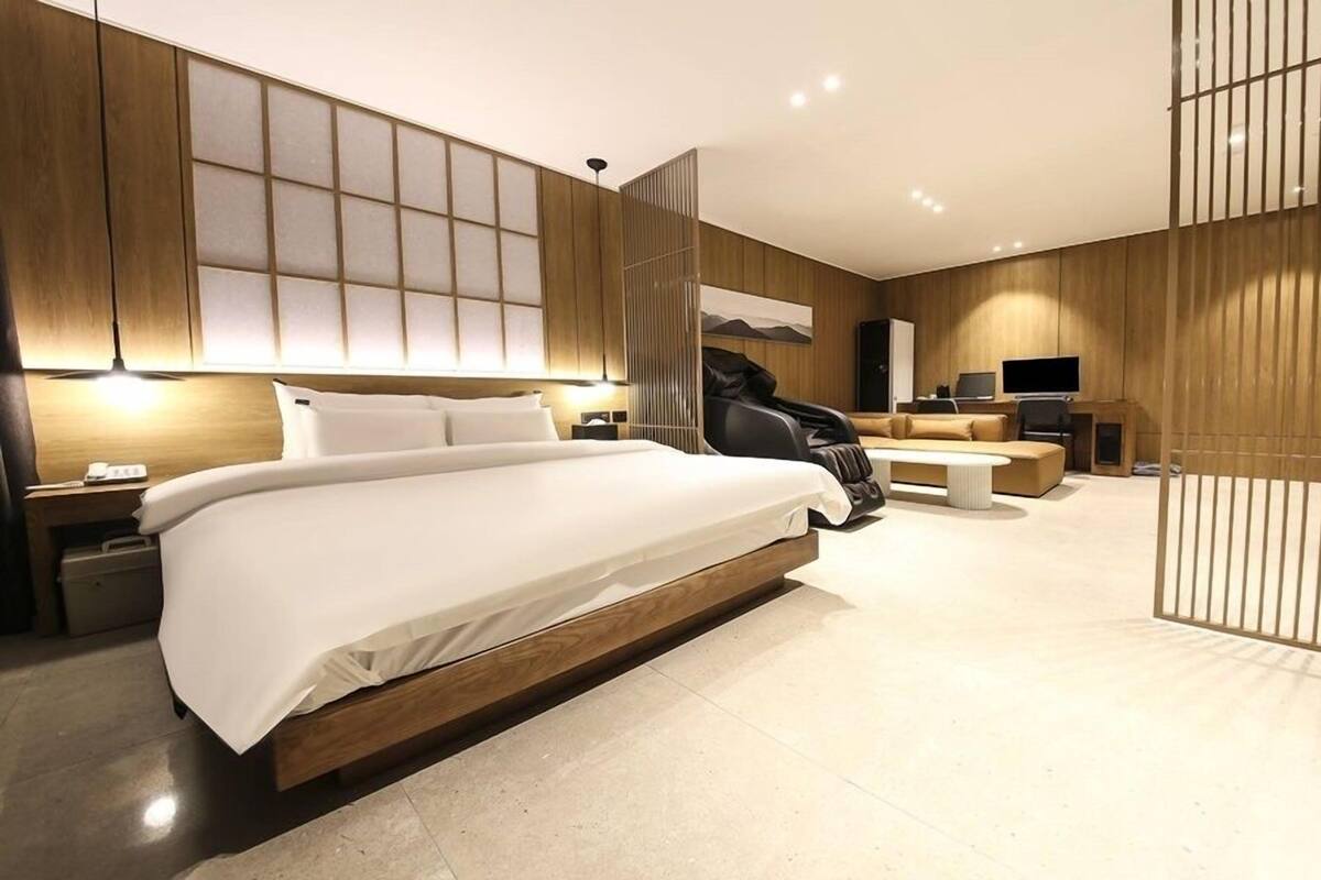 Een moderne hotelkamer met een groot bed, een massagestoel, een bank en een bureau met een televisie.