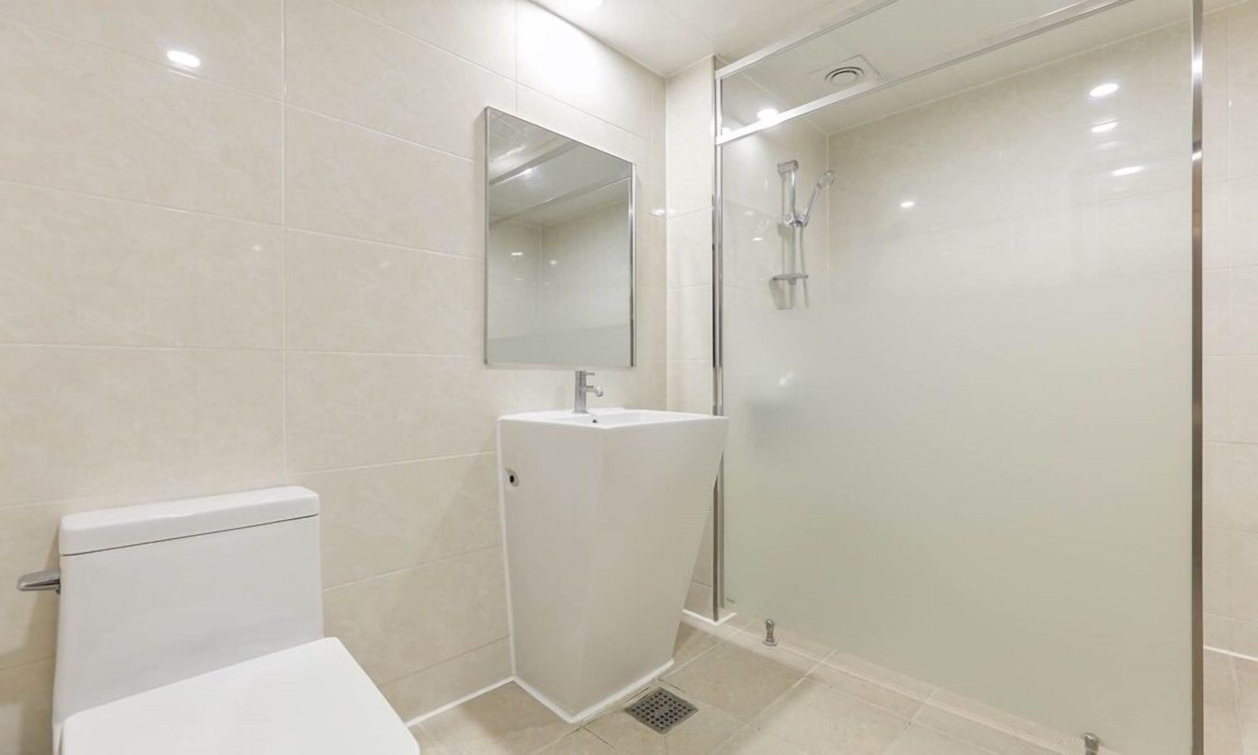 Et stilfuldt badeværelse med toilet, vask og brusekabine med glasvægge.
