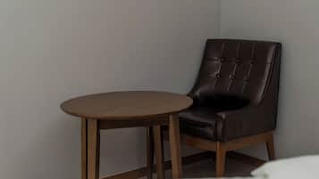 Una silla con asiento y respaldo acolchados, junto a una pequeña mesa redonda de madera.