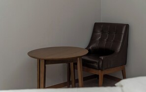 A chair with a cushioned seat and back, paired with a small round wooden table. - Wonju Central Hotel (Wonju)