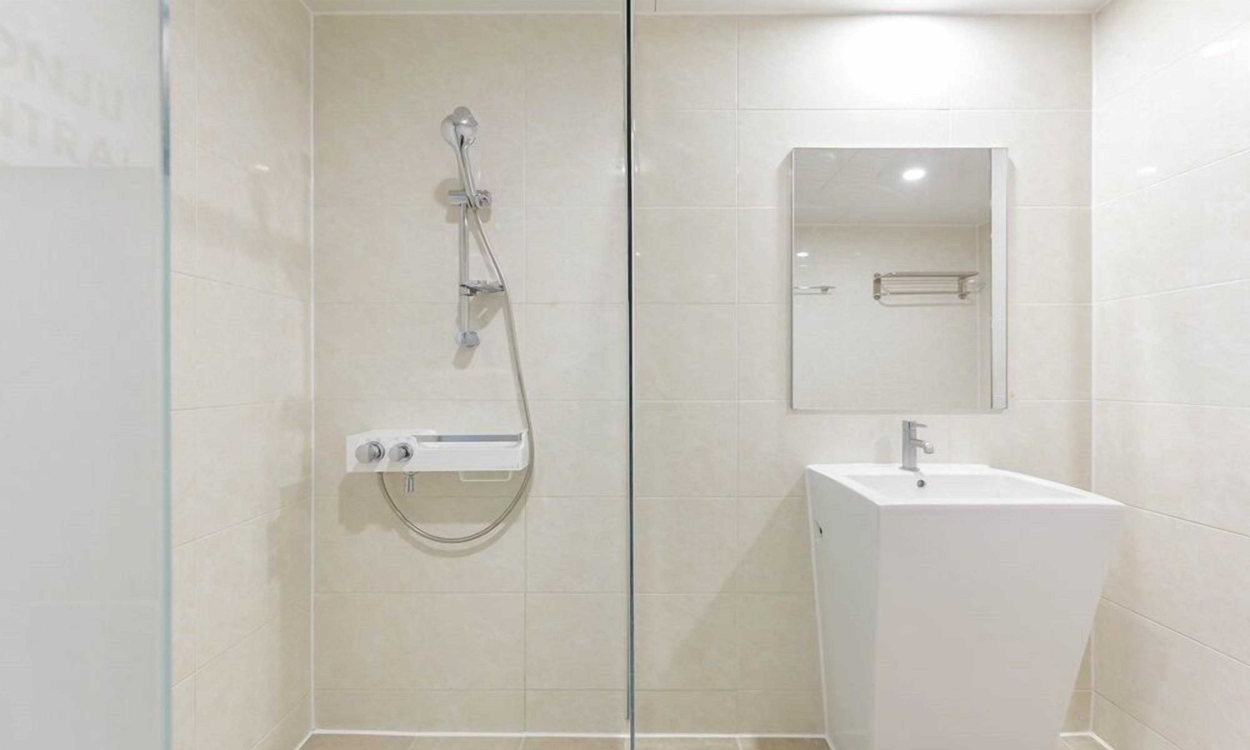 A modern bathroom with a glass shower enclosure, a white sink, and a mirror above the sink.