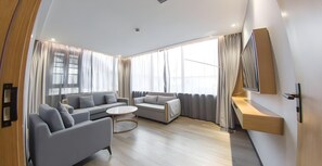 A modern living room with a sofa set, a coffee table, and a TV mounted on the wall.