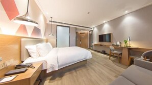A modern hotel room with a bed, desk, chair, and TV.