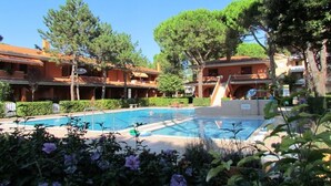Une piscine entourée d’une végétation luxuriante et un bâtiment doté de nombreux balcons.
