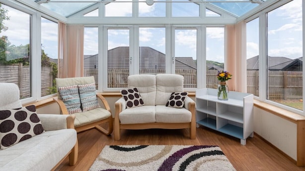 Een oranjerie met een gebogen plafond, een zithoek en een kleine tafel met een bloevas.