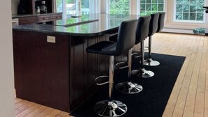 Una cocina moderna con armarios de madera oscura, una isla central y taburetes de bar.