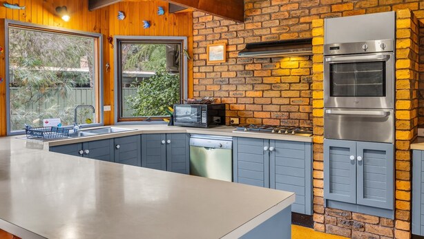 A kitchen with a brick wall, wooden ceiling, and stainless steel appliances.