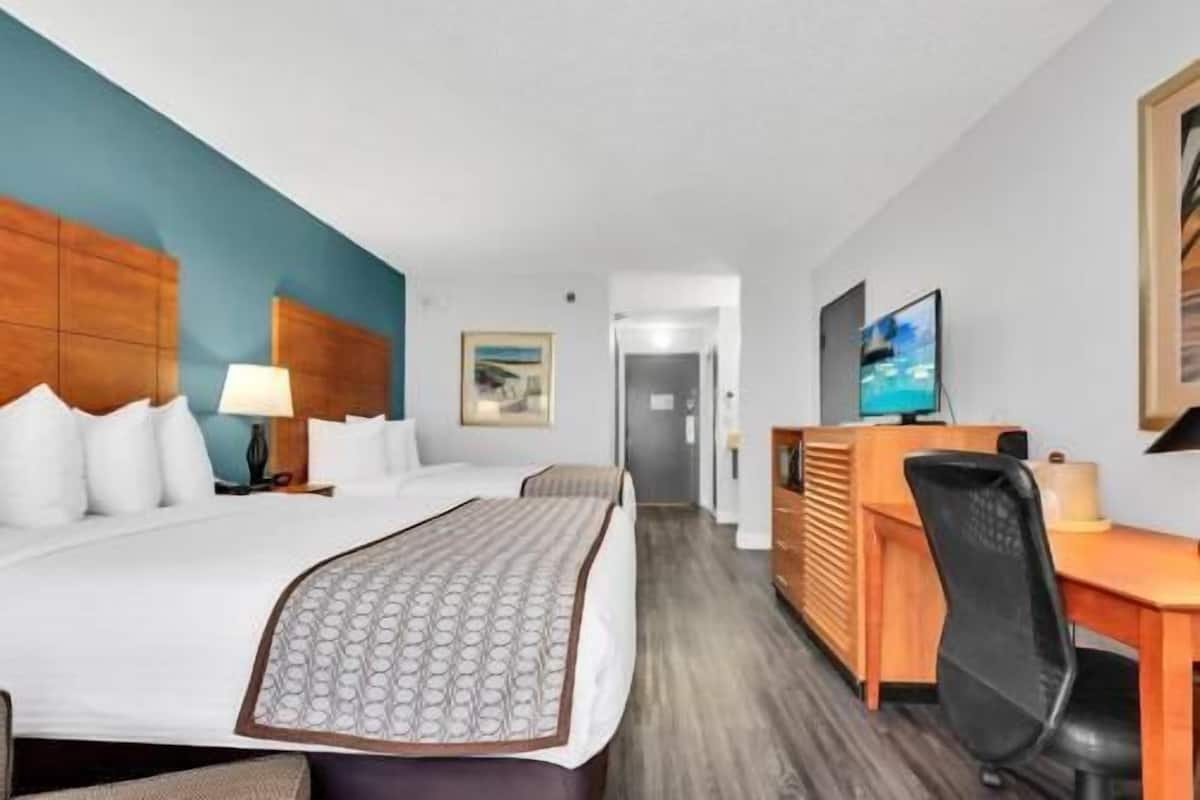 A hotel room with a bed, desk, chair, and television.