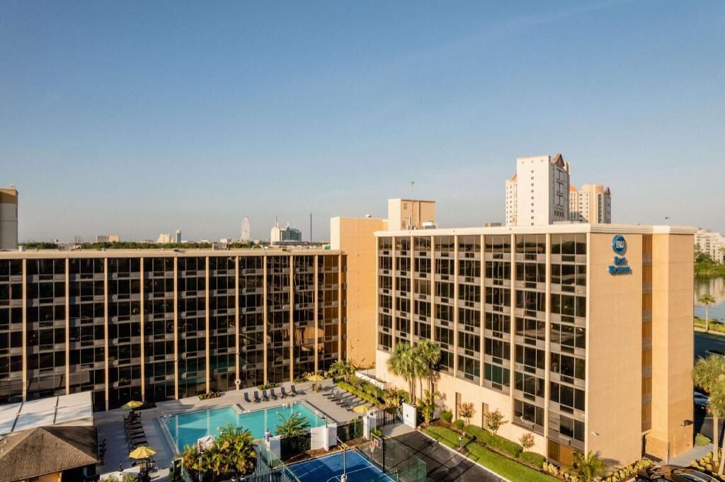 A hotel with a pool, multiple floors, and a view of the city skyline.