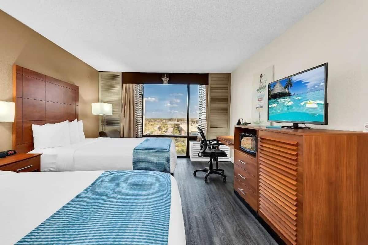 A hotel room with a bed, a desk, a television, and a view of the outdoors.