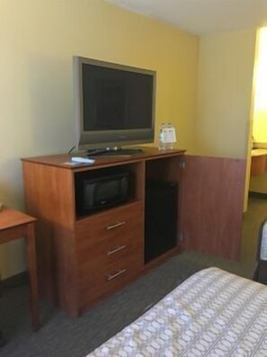A hotel room with a bed, a wooden dresser with a television, a microwave, and a small table. - Best Western Orlando Gateway Hotel (Orlando)