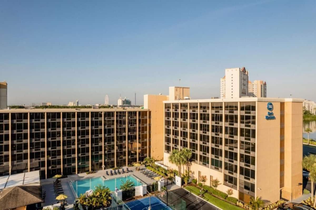 A hotel with a pool, multiple floors, and a view of the city skyline.