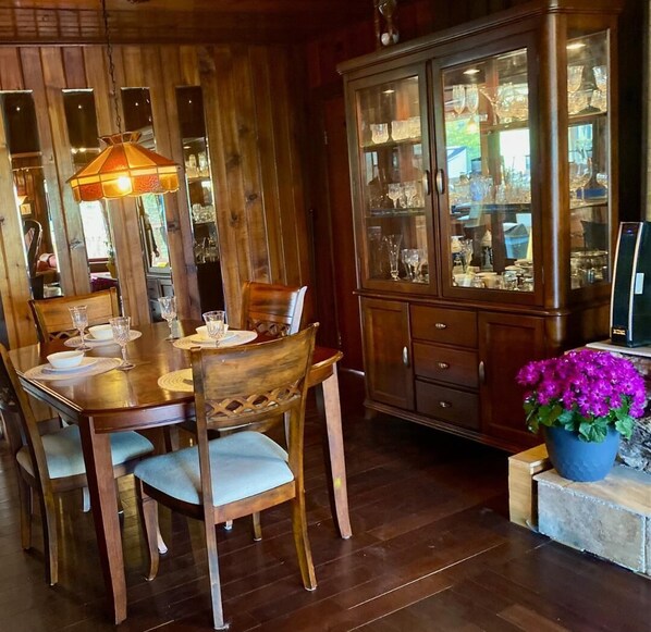 A wooden dining area with a table set for four, surrounded by chairs.