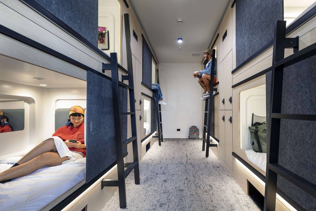A train compartment with bunk beds, a small seating area, and a compact kitchenette.