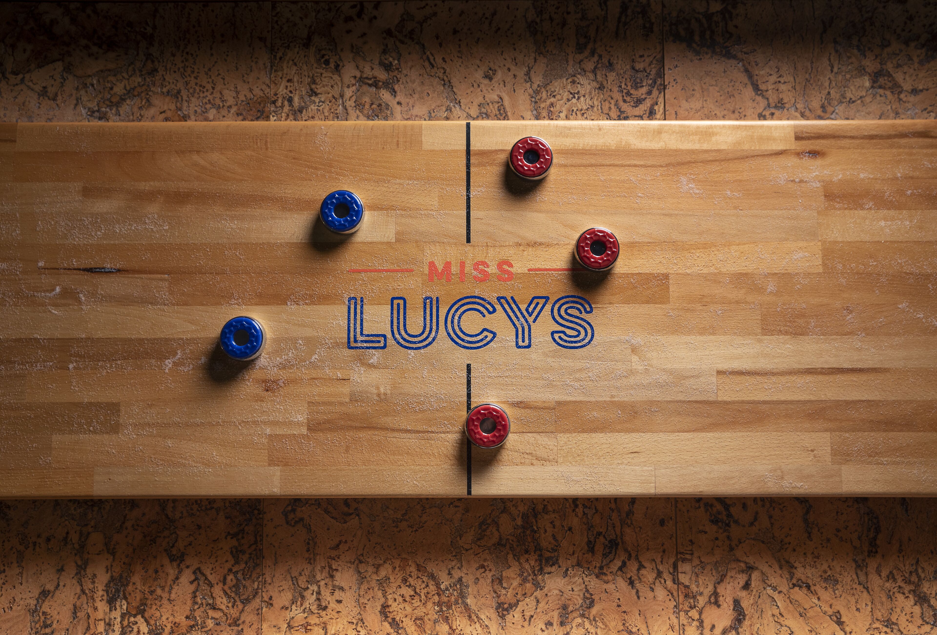Un piso de madera con el nombre "MRS. LUCY'S" y cuatro tapas metálicas.