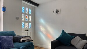 Ein Wohnzimmer mit zwei Sofas, einer Tür mit Glasfenstern und einer Wandleuchte.