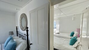Ein Zimmer mit einem Bett, einem Nachttisch, einer Lampe und einem Spiegel.