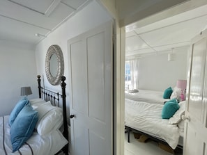 A room with a bed, a bedside table, a lamp, and a mirror. - Charming coastal cottage perfect for a break by the seaside, in Deal (Deal)