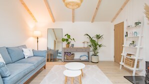 A modern living room with a blue sofa, a white coffee table, a wooden console table with plants, and a bookshelf. - The perfect retreat for couples wanting to enjoy Deal (Deal)