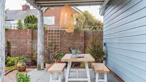 An outdoor patio with a wooden table and benches, surrounded by potted plants and a hanging basket. - The perfect retreat for couples wanting to enjoy Deal (Deal)