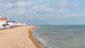 A beach with pebbles, a promenade with buildings, and the sea. - Light, bright, and colourful apartment opposite Deal pier (Deal)