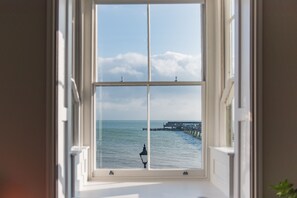 A window with a view of the sea and a pier. - Light, bright, and colourful apartment opposite Deal pier (Deal)