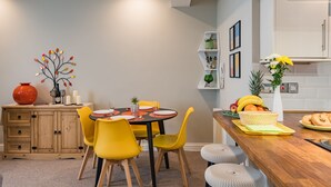 A modern kitchen with a wooden countertop, yellow chairs, and a dining table set for four. - Light, bright, and colourful apartment opposite Deal pier (Deal)