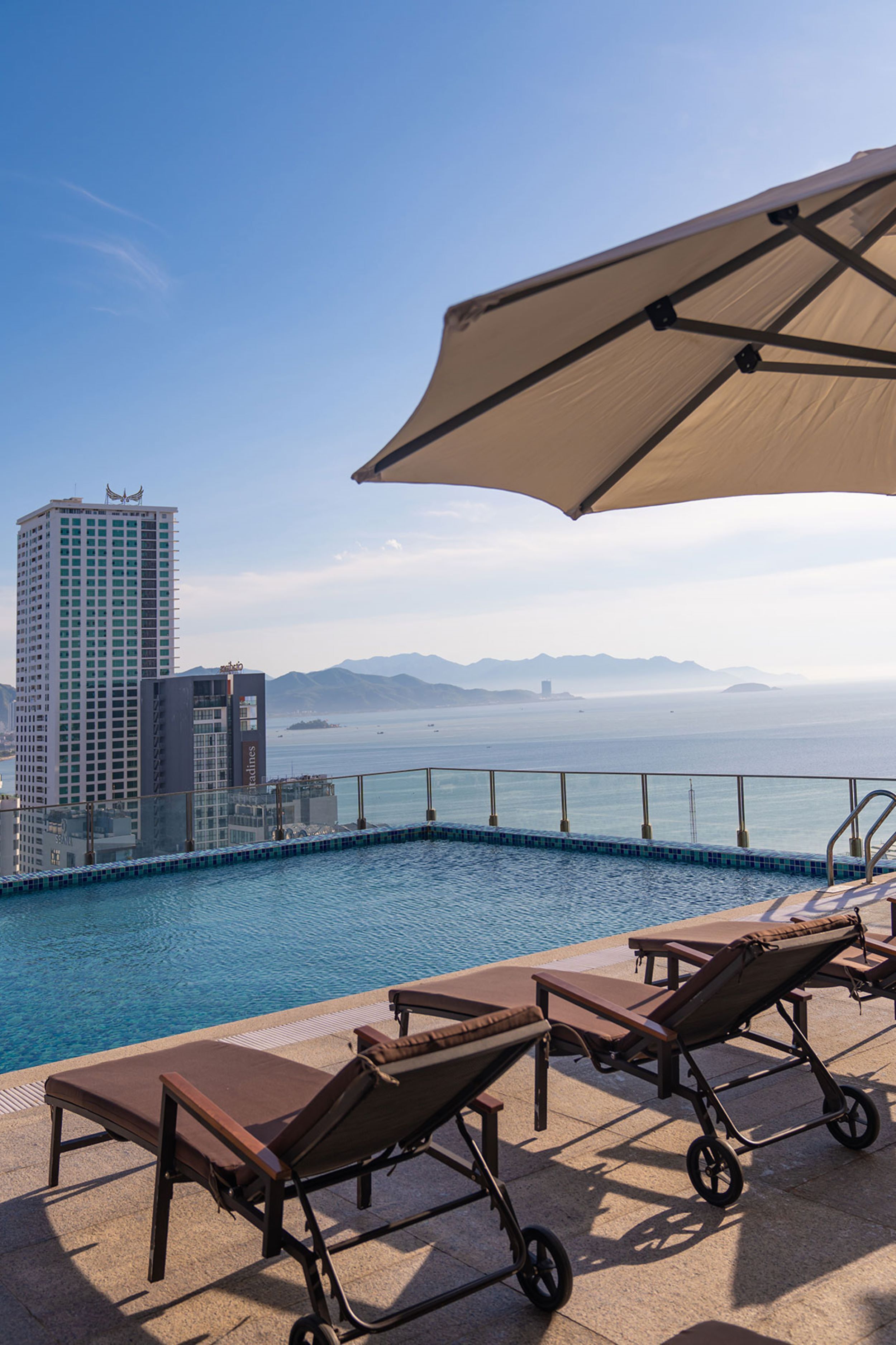 Ein Poolbereich mit Liegestühlen und Blick auf Stadt und Berge.