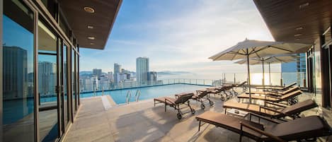 Una piscina al aire libre, sombrillas, sillones reclinables de piscina