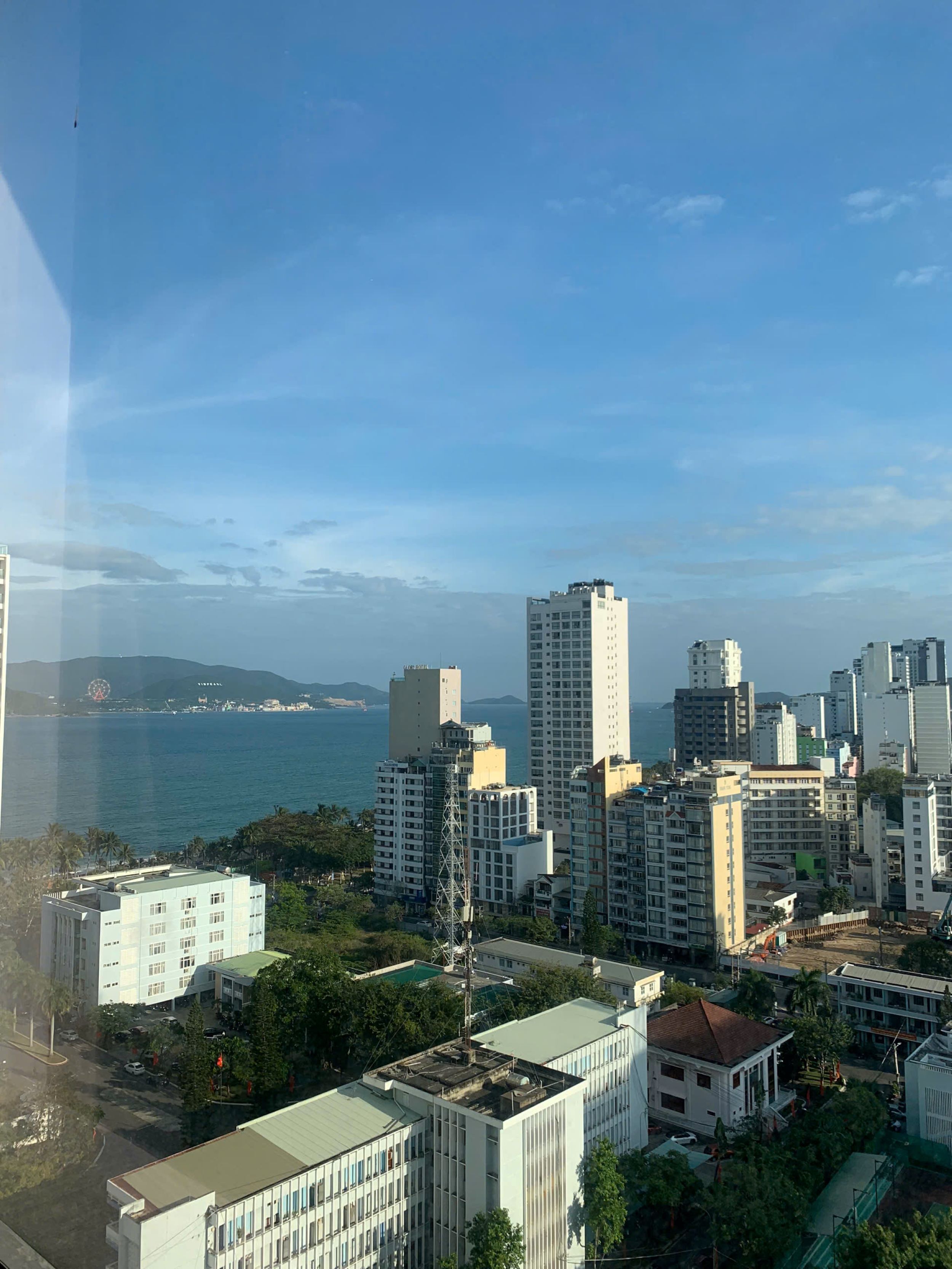 A cityscape with high-rise buildings, a clear sky, and a body of water in the background.