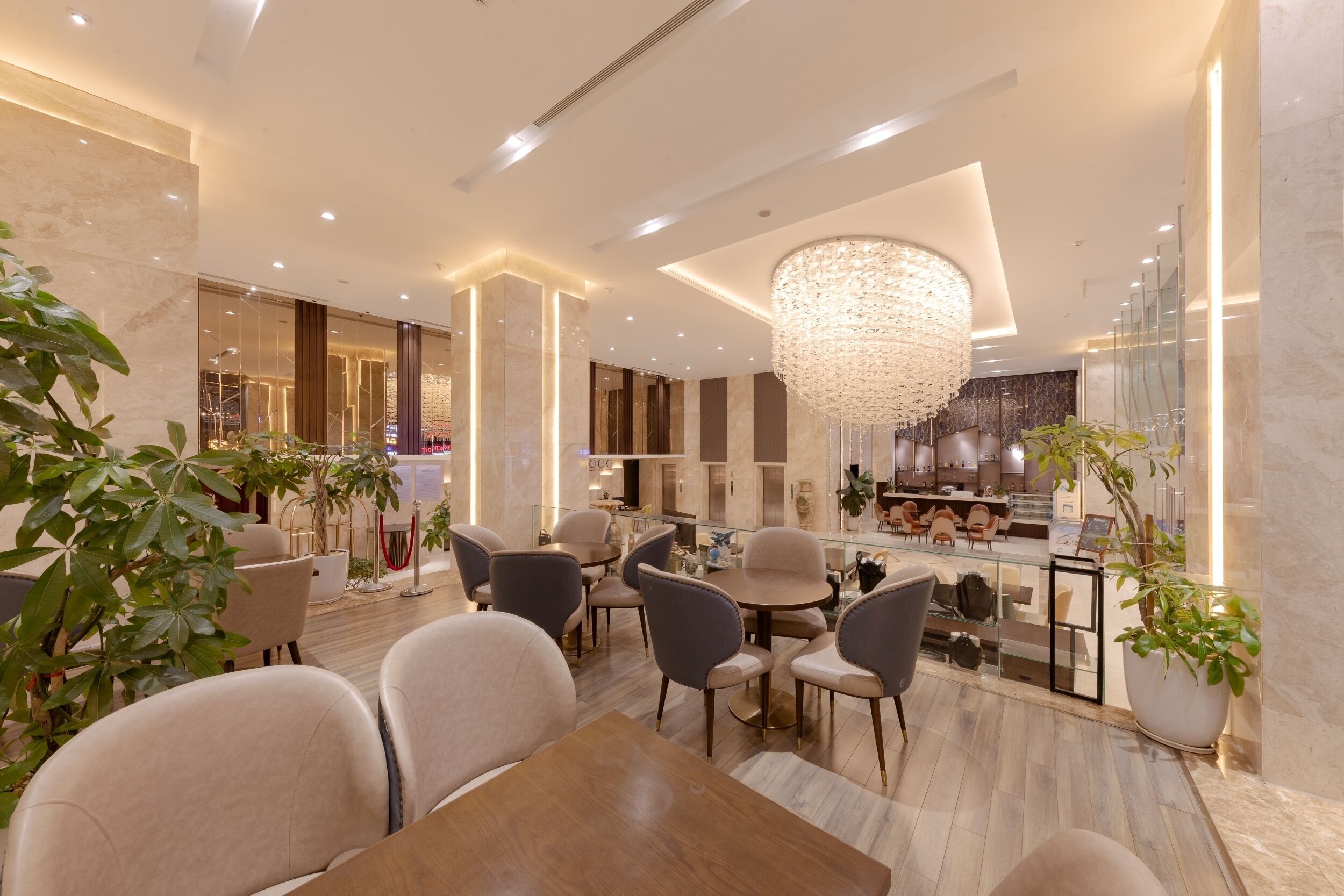 A modern hotel lobby with a chandelier, seating area, and a reception desk.