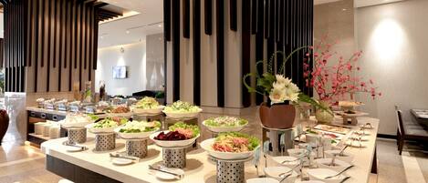 A buffet setup with various food items and serving utensils.