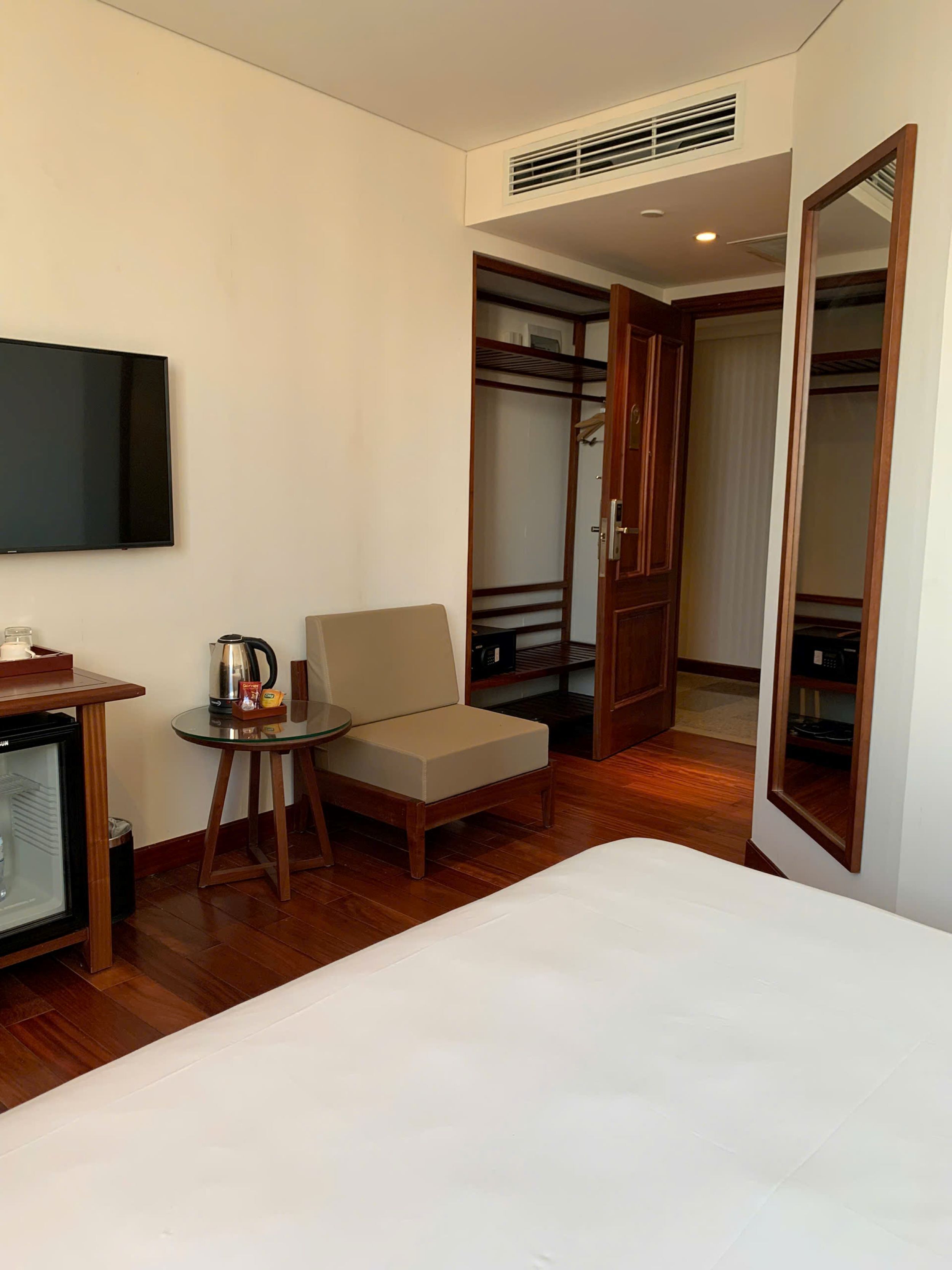 Habitación de hotel con cama, televisor, una mesita con silla, kitchenette y armario.