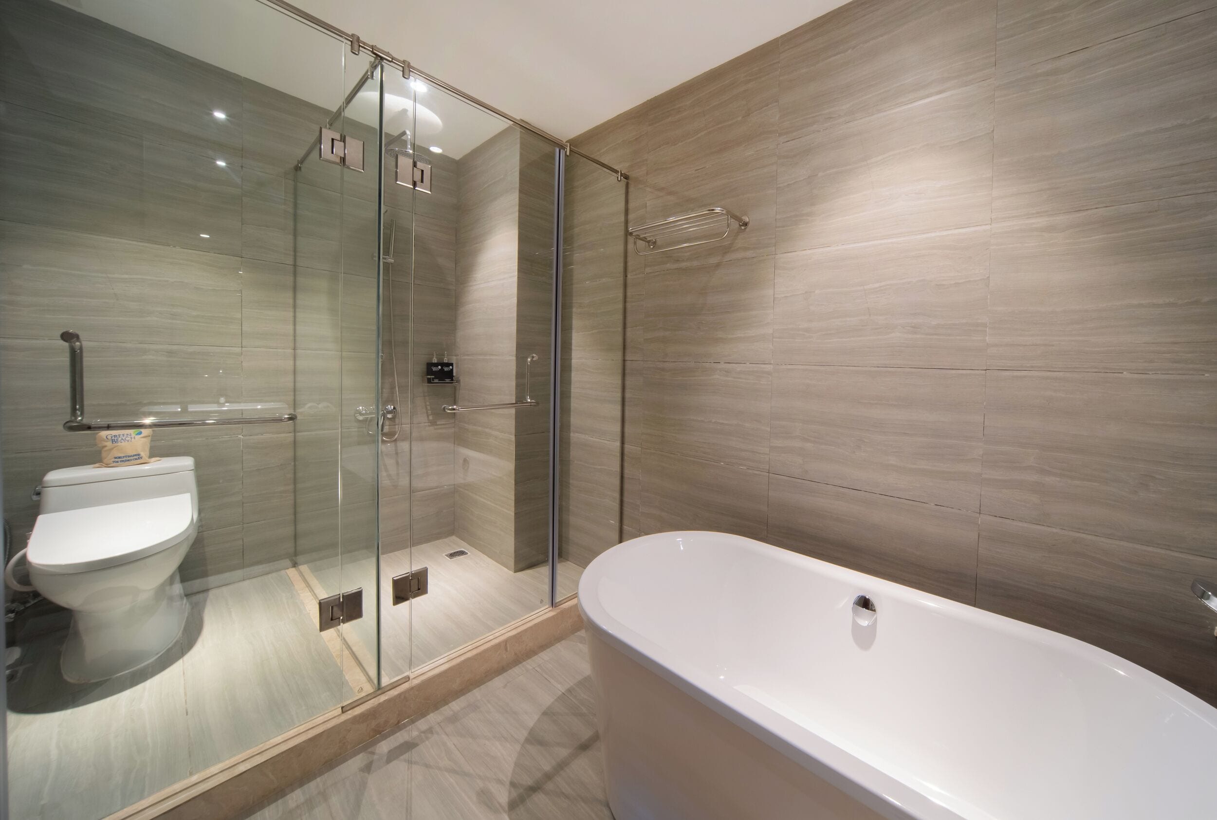 Un baño moderno con ducha envuelta en vidrio, bañera independiente y retrete.
